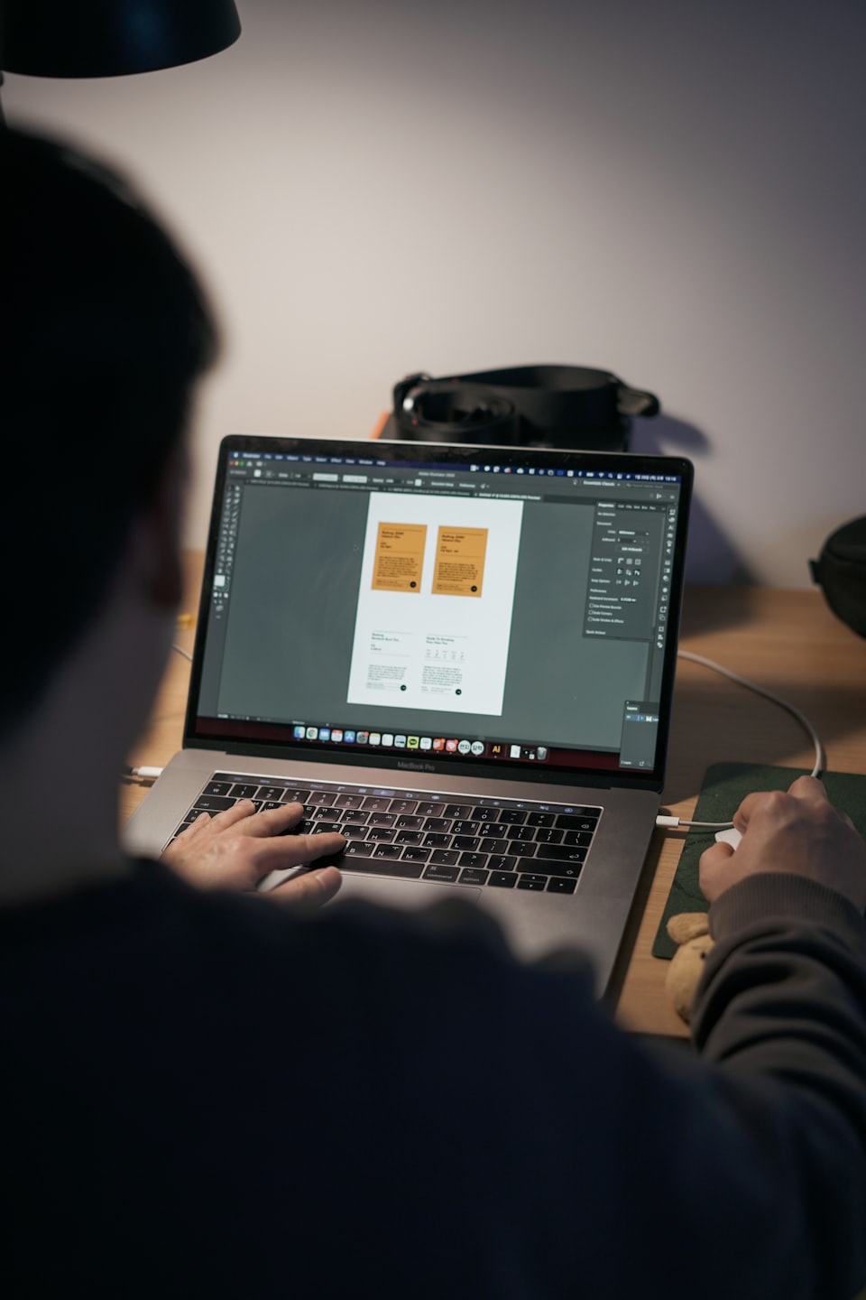 Designer working on Adobe Illustrator on a MacBook Pro.